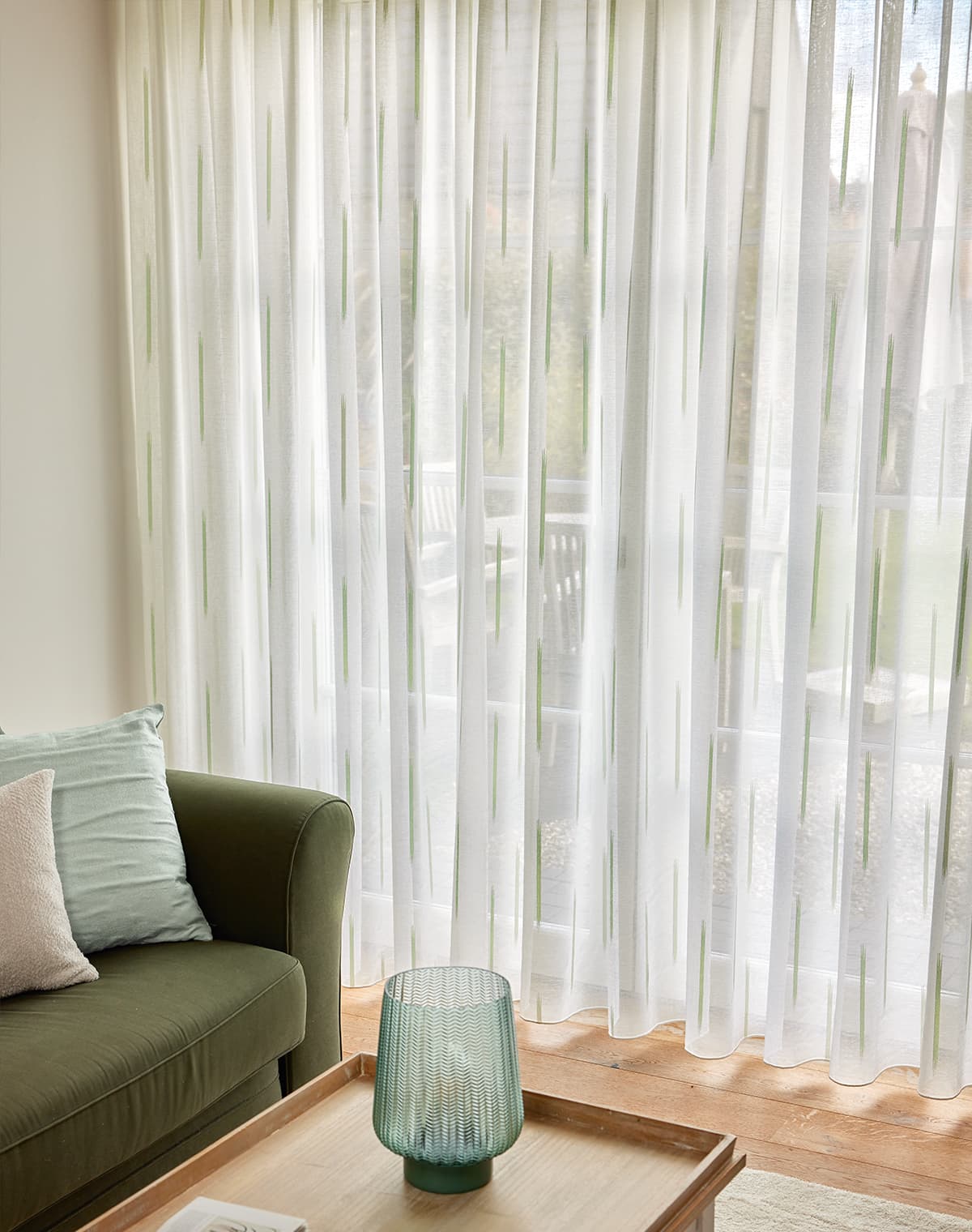 Ein grünes Sofa und eine weiße Gardine im Wohnzimmer.