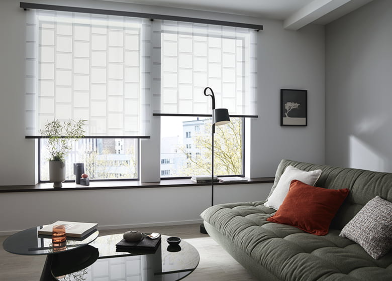 Wohnzimmer mit grünem Sofa und weißen Rollos