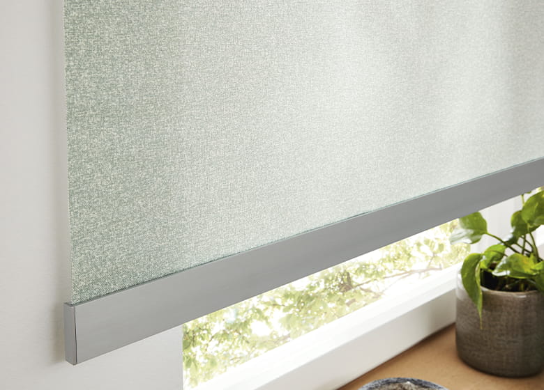 Hellgrünes Rollo mit silberner Schiene am Fenster